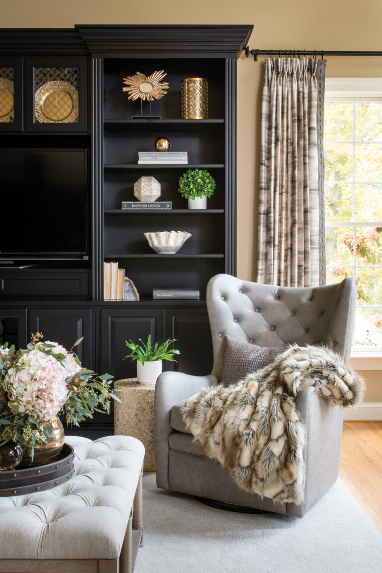 In the living room of a Georgian-style abode, a modern take on a wingback chair sits before built-ins in a lacquered charcoal finish and screen-printed linen drapery.