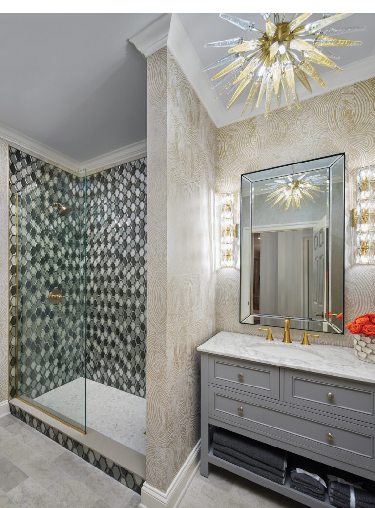 A chic bath combines unexpected flourishes: a sunburst chandelier, a bold mosaic glass-tile shower and embossed Thibaut wallpaper.
