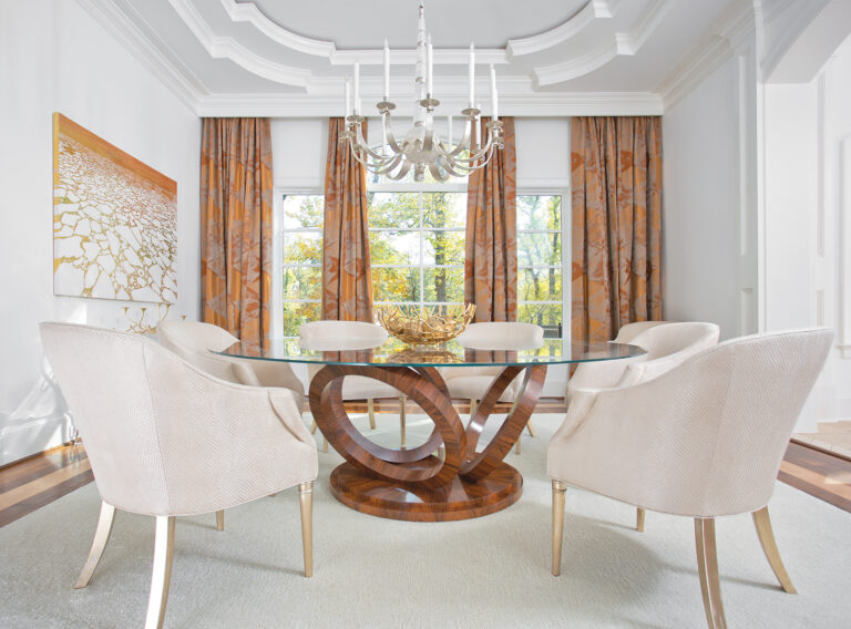 An elegant dining room pairs exquisite architectural millwork and classical moldings with bespoke, contemporary furnishings. Sumptuous silk draperies frame the windows in soft folds, while curated art and a sculptural rock crystal chandelier create a refined space that feels both timeless and fresh.