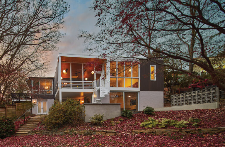 A mid-century abode in Garrett Park features a rear addition overlooking Rock Creek Park through Windsor windows. Below the primary suite and screened porch, the family room leads out to a patio.
