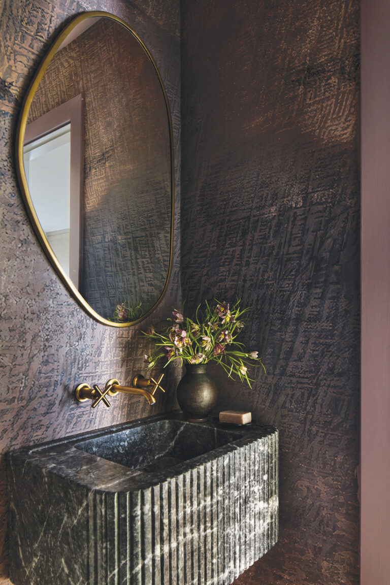 A custom, fluted-marble sink and textural wallpaper bring drama to a powder room. Styling: Kristi Hunter.