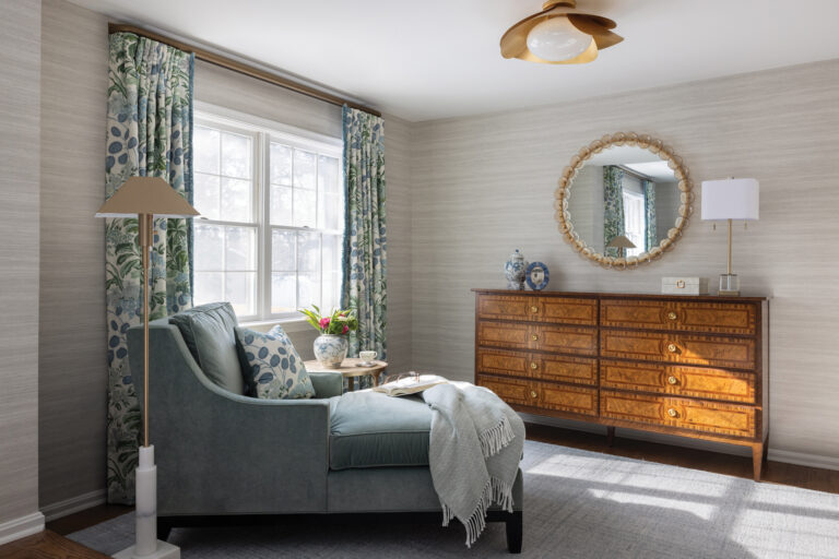 A Vienna bedroom beckons with a burl wood dresser and a chaise longue beside a window dressed in botanical drapery.