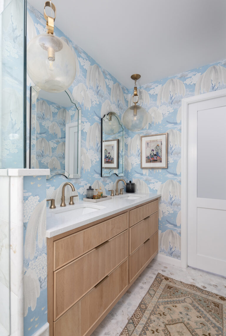 Painterly wallpaper adds drama to an Oak Hill, Virginia, powder room, paired with a light-wood vanity and brass fixtures.
