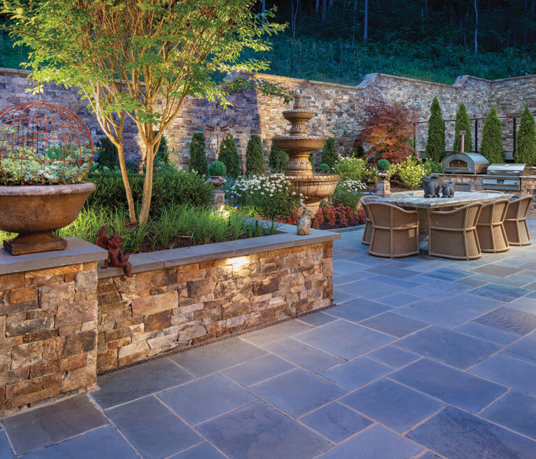 A tiered travertine fountain is a central design element, offering soothing sounds beside the al fresco dining area.
