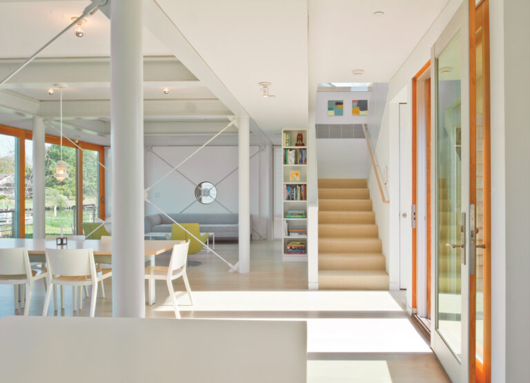 The open-plan main level of a Neavitt, Maryland, home lines up the kitchen, living and dining areas along a wall of windows overlooking the Chesapeake Bay.
