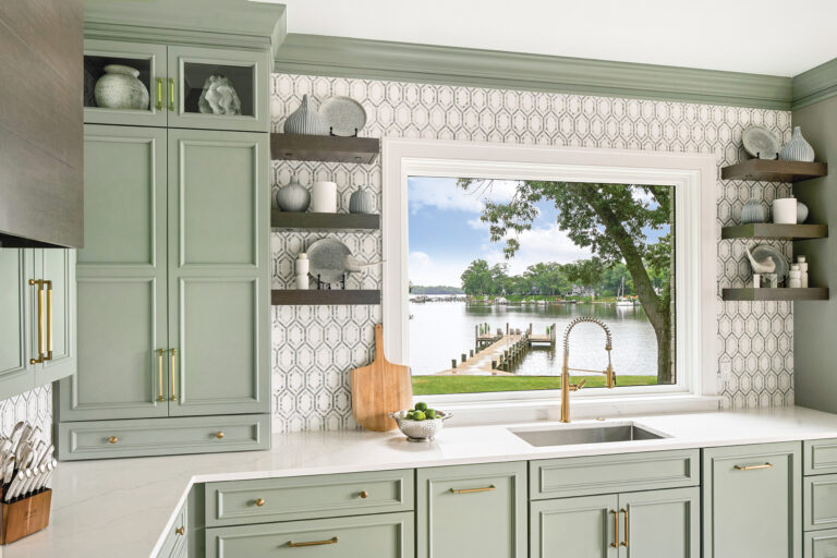 Anchoring the range wall, a custom, walnut-finished hood connects to the island and table; it provides contrast with the sea green cabinetry and marble mosaic surfaces.