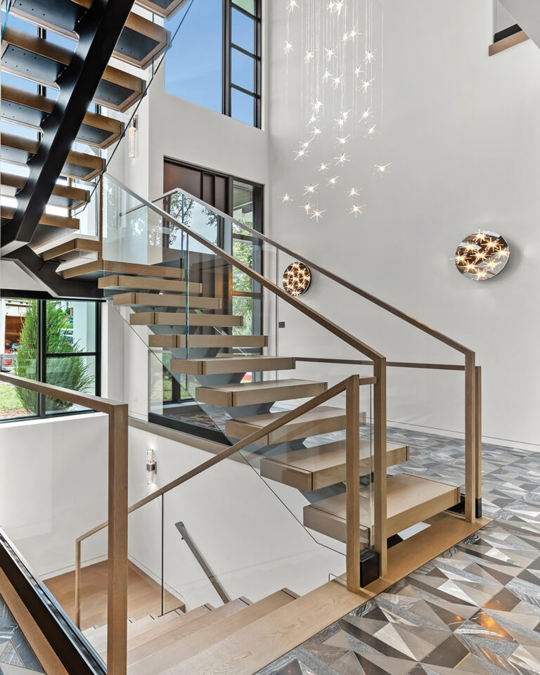 The two-story entry hall houses a floating staircase and expansive windows overlooking the front yard.