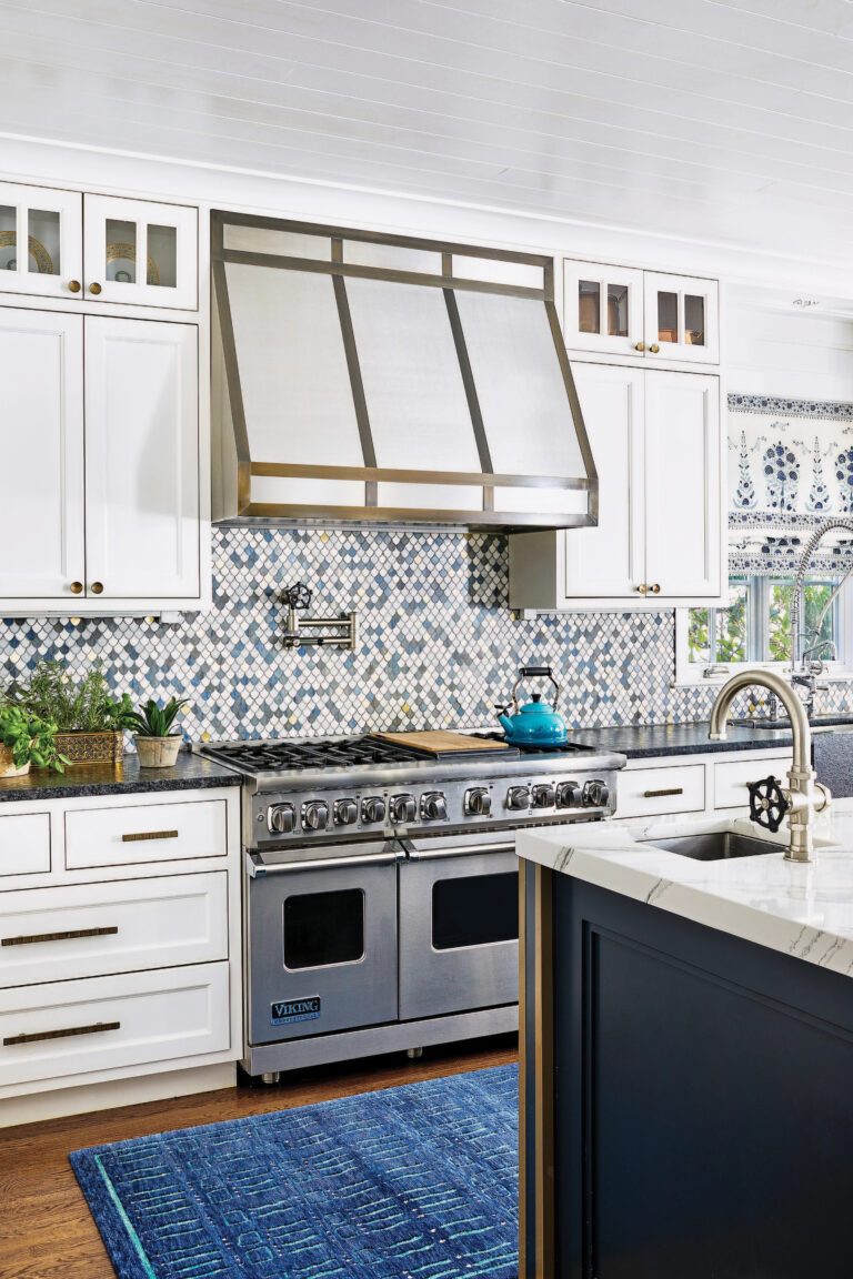 A light and bright kitchen boasts mosaic-tile backsplash, crisp-white cabinetry and an eye-catching hood.