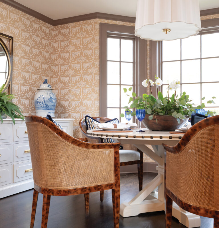 A breakfast room in a Ruxton, Maryland, home features Port Eliot wicker chairs around a table with nail-head detailing. Schumacher grasscloth clads the walls.