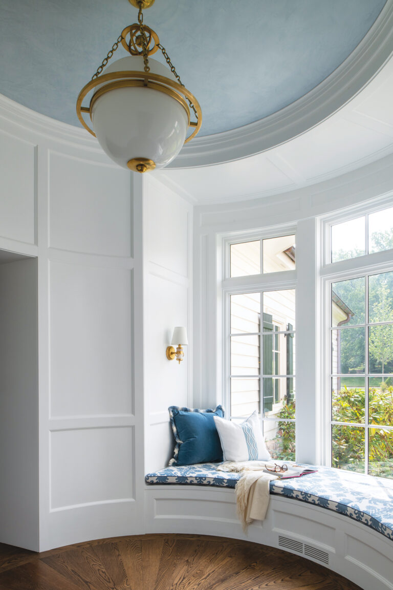 A rotunda is elevated by millwork and a built-in window seat. An overhead fixture by Visual Comfort is a refined finishing touch.
