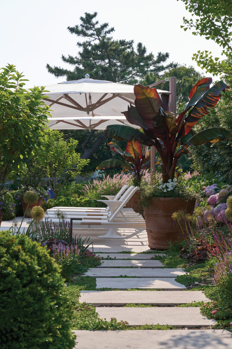 Travertine steppingstones lead to a chaise lounge terrace within a lush and intimate garden retreat.