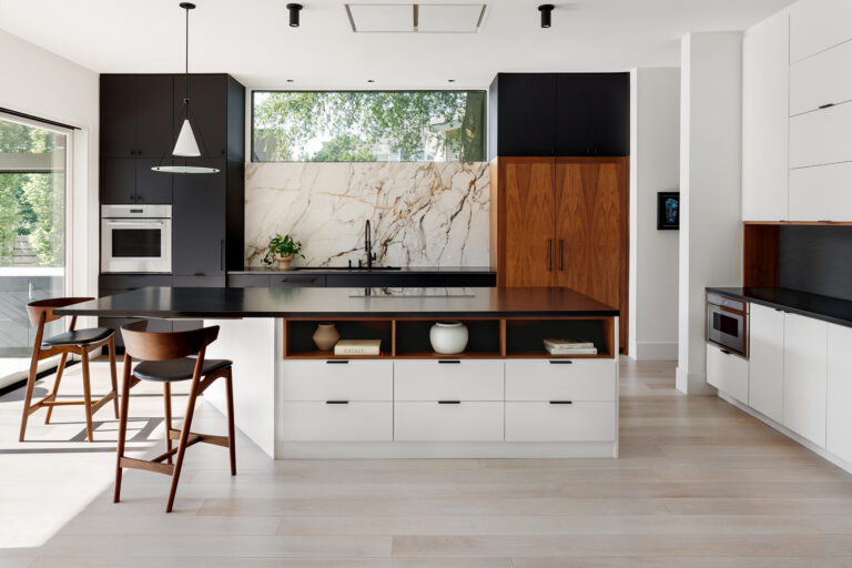 6. Walnut open shelving, matte black accents, and a Calacatta marble backsplash compose a kitchen that balances warmth with deliberate restraint.