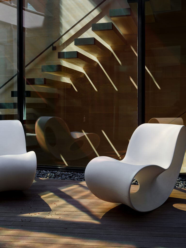 A cantilevered stair becomes the home's sculptural centerpiece, with each tread catching the light and casting layered shadows across the atrium below.