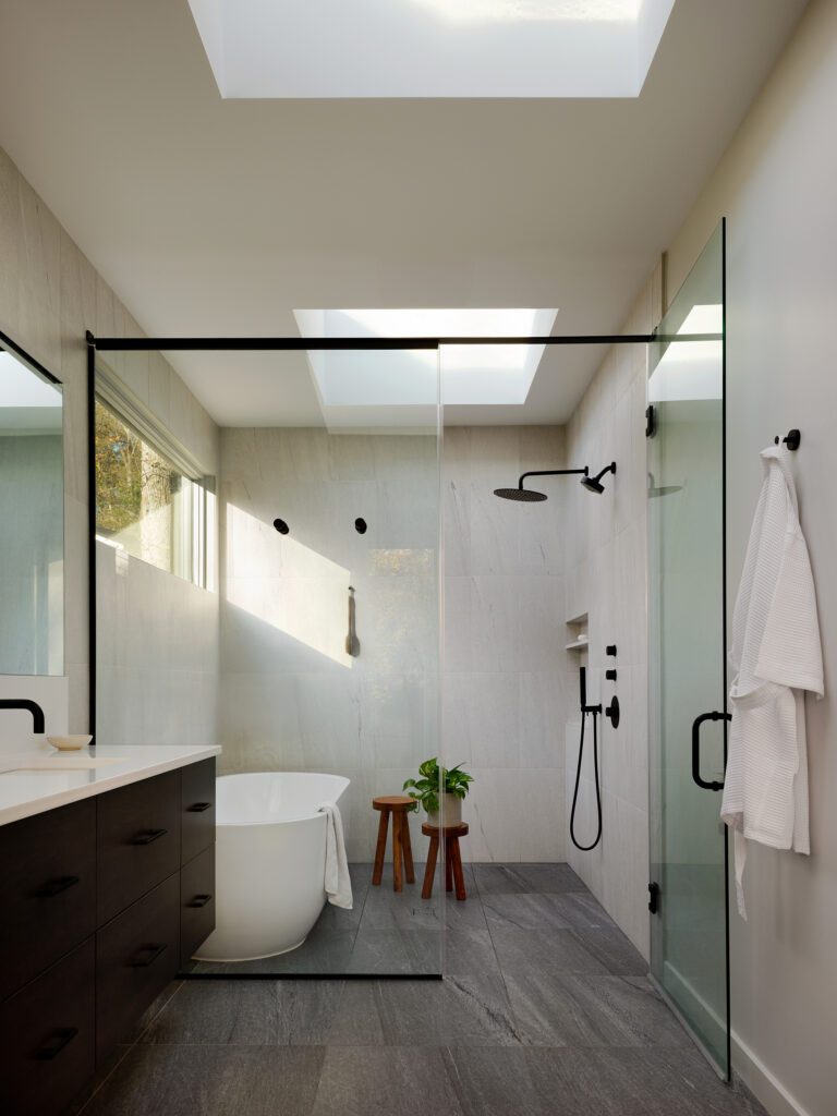 A skylit wet room pairs a glass-enclosed shower with Ann Sacks La Palma tile, the deep charcoal floor grounding the space.