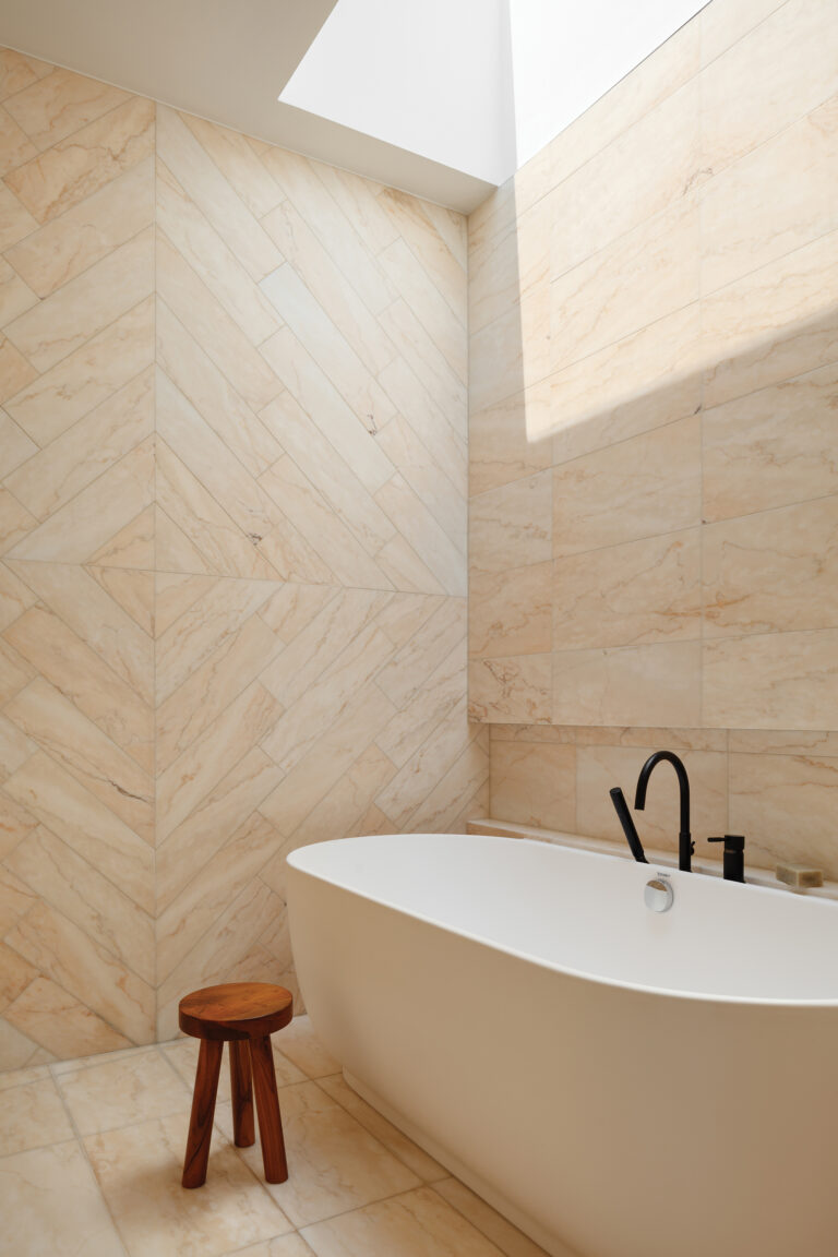 In a serene bathroom, a skylight washes over a sculptural Duravit bathtub set against Rosa Portogallo stone.