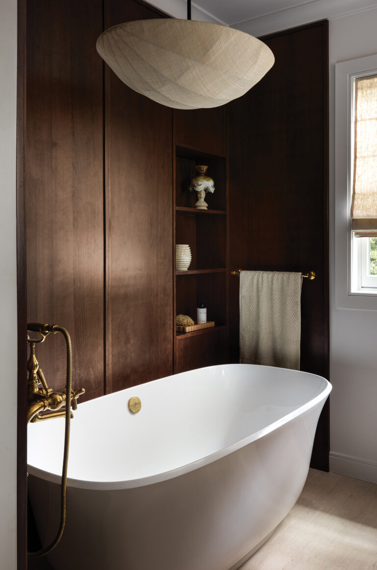 A custom walnut storage alcove beside a freestanding tub elevates a primary bath in DC.